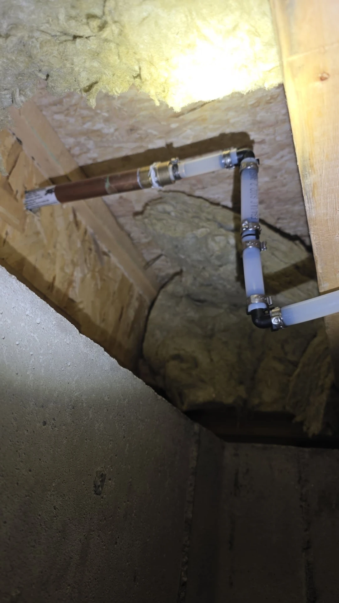 PEX water lines routed through basement floor joists with copper transition fittings