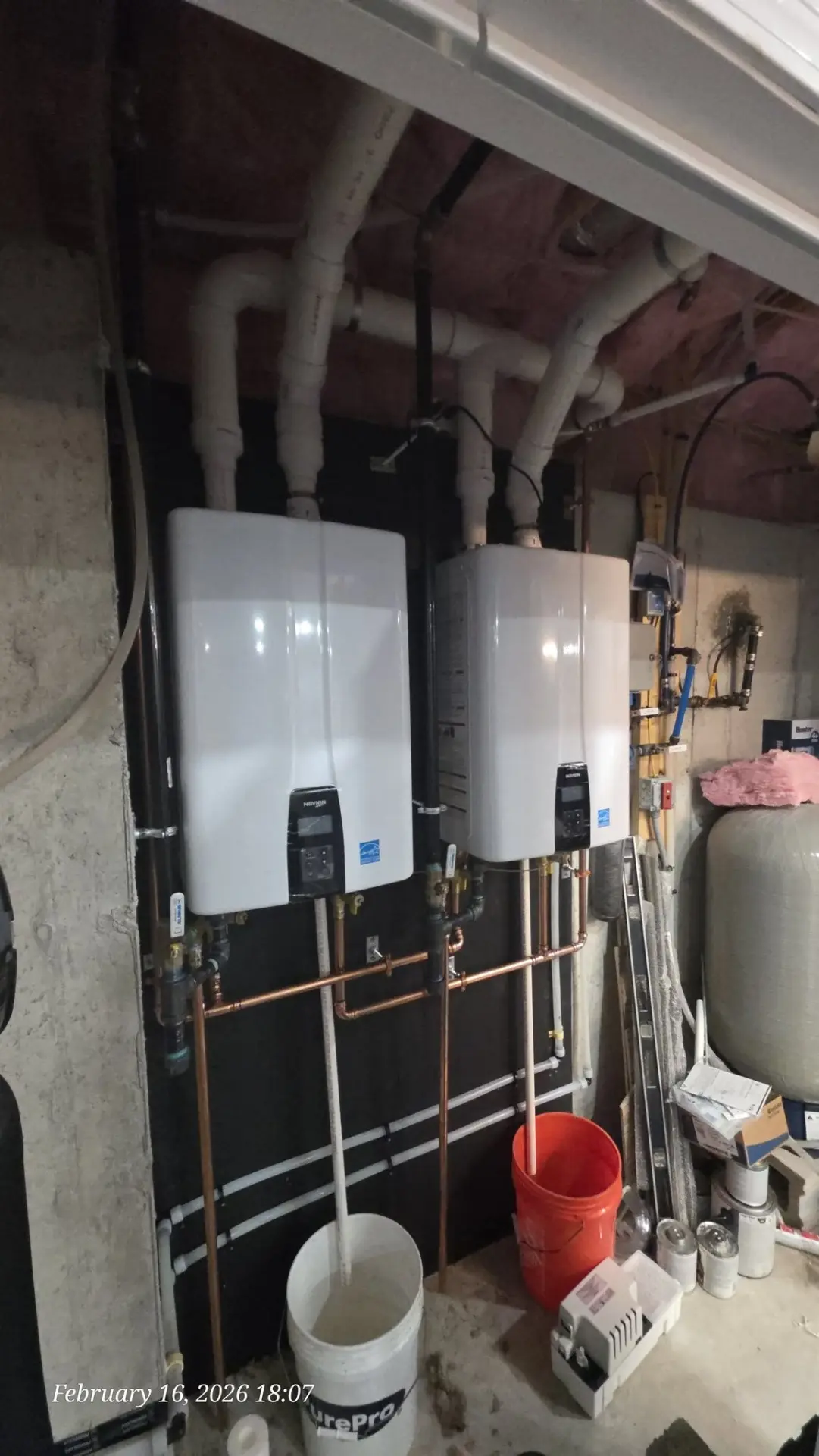 Two wall-mounted Navien tankless water heaters installed side by side with copper piping